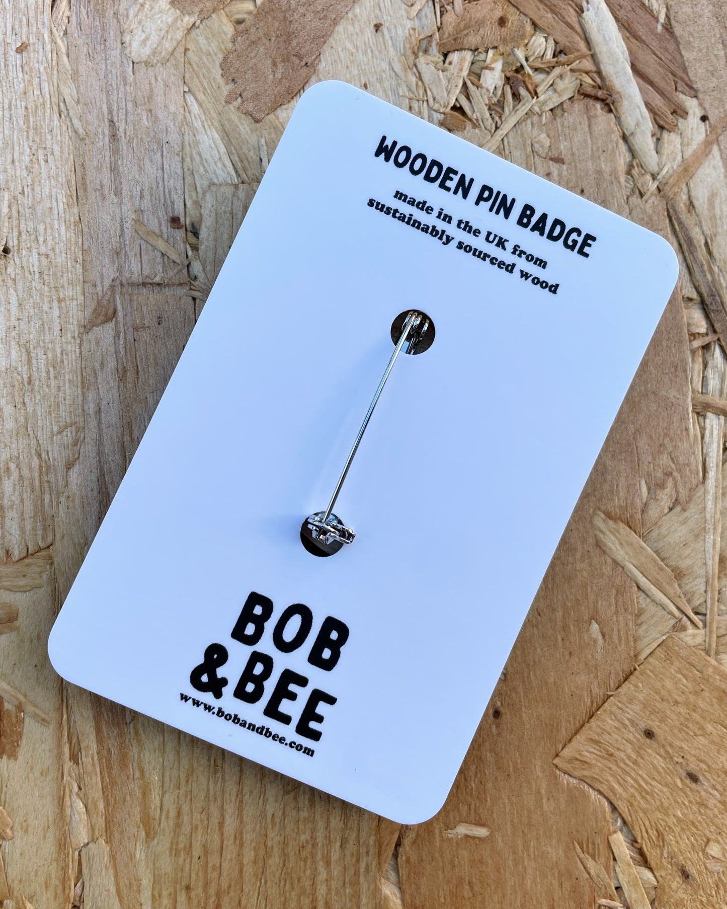 Reverse of a wooden pin badge on a card with 'Bob & Bee' branding on a wooden surface. 